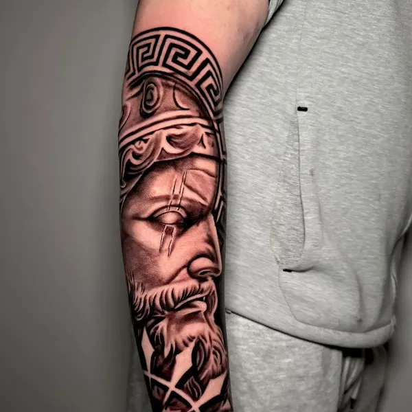 Black and grey Greek warrior statue forearm tattoo with Greek key meander border, by Cameron at Shade Studio Peterborough