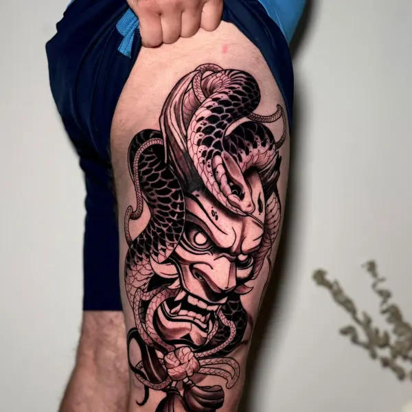 Hannya mask wrapped by a snake, black and grey thigh tattoo by Cameron at Shade Studio Peterborough