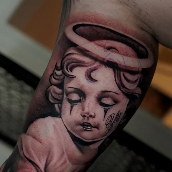black and grey cherub angel portrait with halo, inked along the forearm
