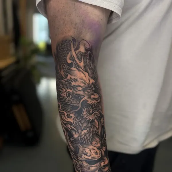 Japanese dragon forearm sleeve in black and grey with cloud and wave detail, by Kai at Shade Studio Peterborough