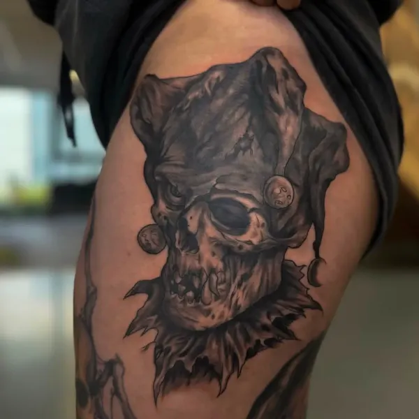 Black and grey jester skull with harlequin hat, thigh tattoo by Kai at Shade Studio Peterborough