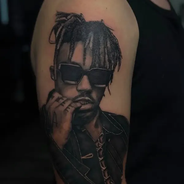 Black and grey portrait tattoo of a rapper wearing sunglasses, upper arm by Kai at Shade Studio Peterborough