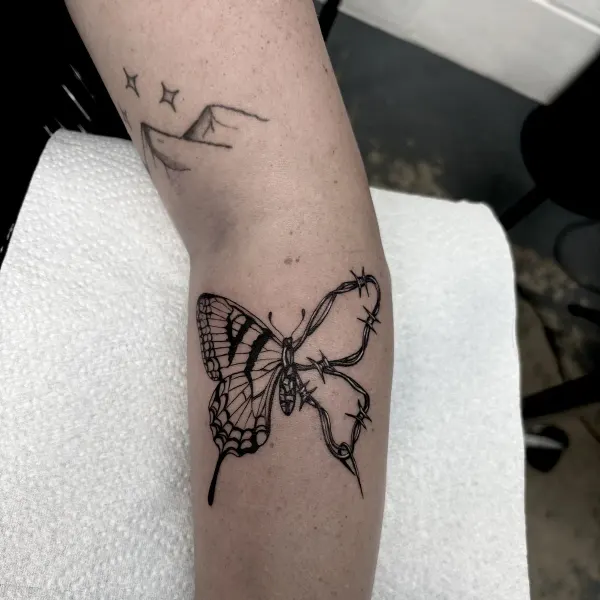 Butterfly wrapped in barbed wire, blackwork calf tattoo by Lana at Shade Studio Peterborough