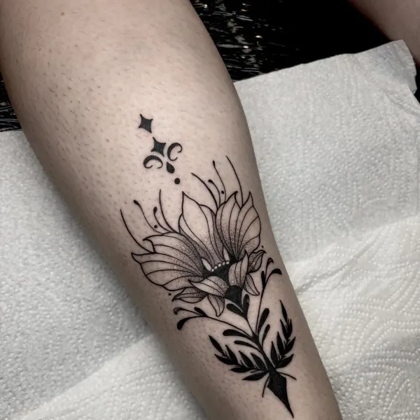 Lily with solid black leaves and stipple shading, calf tattoo by Lana at Shade Studio Peterborough