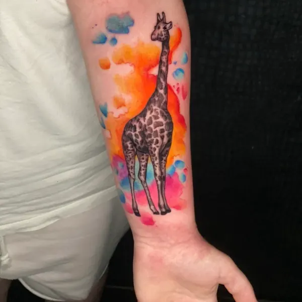 Giraffe with orange and blue watercolour splash, forearm tattoo by Karolina at Shade Studio Peterborough