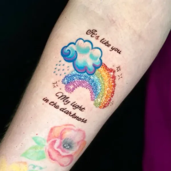 Rainbow and cloud with script lettering, colour forearm tattoo by Karolina at Shade Studio Peterborough