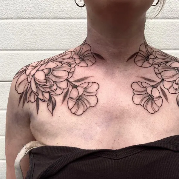 Symmetrical fine line floral piece across the collarbones and shoulders by Ashlee at Shade Studio Peterborough