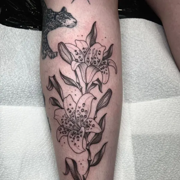 Fine line lilies with leopard print detail and stipple shading, calf tattoo by Ashlee at Shade Studio Peterborough