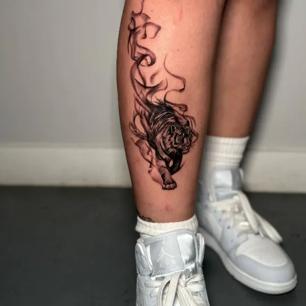 Fine line tiger emerging from smoke, calf tattoo by Cameron at Shade Studio Peterborough